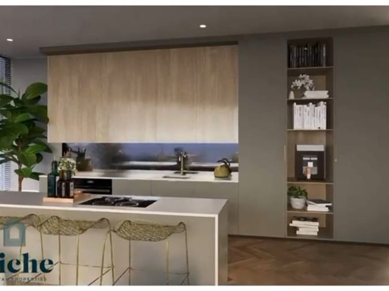 Modern open-plan kitchen featuring sleek cabinetry, a central island with integrated cooktop, and built-in shelving, finished with high-quality materials and contemporary design.