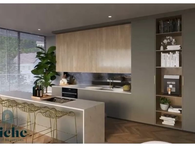 Modern open-plan kitchen featuring sleek cabinetry, a stone-topped island with integrated cooktop, and floor-to-ceiling storage shelving.