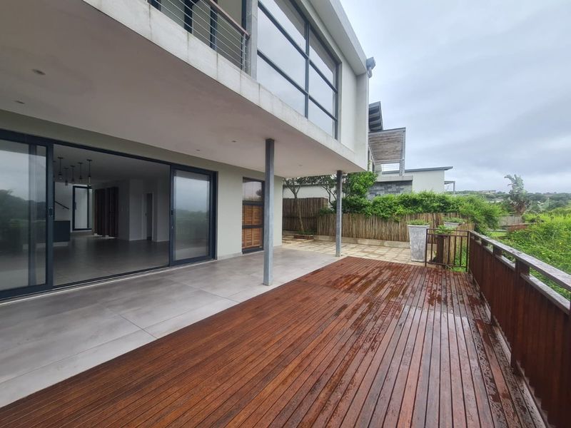 Spacious covered patio featuring a combination of tiled flooring and timber decking, providing seamless indoor-outdoor flow through large sliding glass doors.