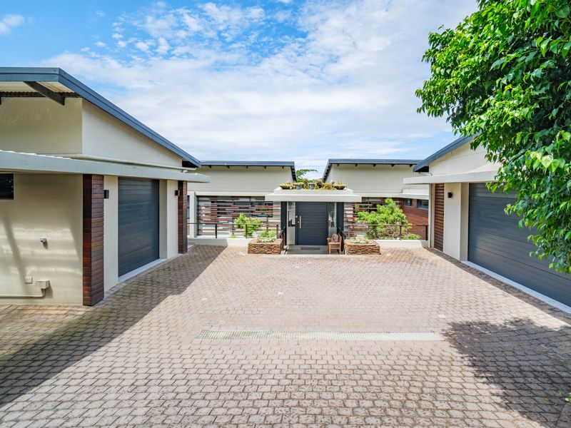 Modern front facade featuring a paved driveway, double garage access, and a welcoming covered entrance with stone detailing.