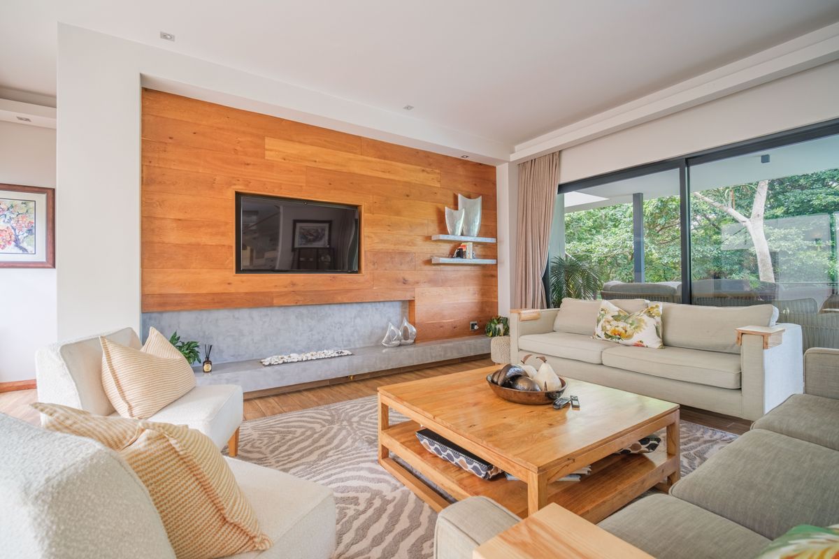 Modern living room featuring a prominent timber feature wall, concrete hearth, and large sliding glass doors providing seamless access to the outdoor area.