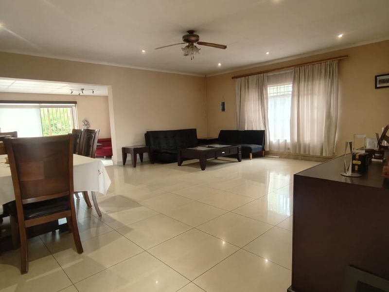 Spacious open-plan living and dining area featuring large format floor tiles, recessed ceiling lighting, and a central ceiling fan.