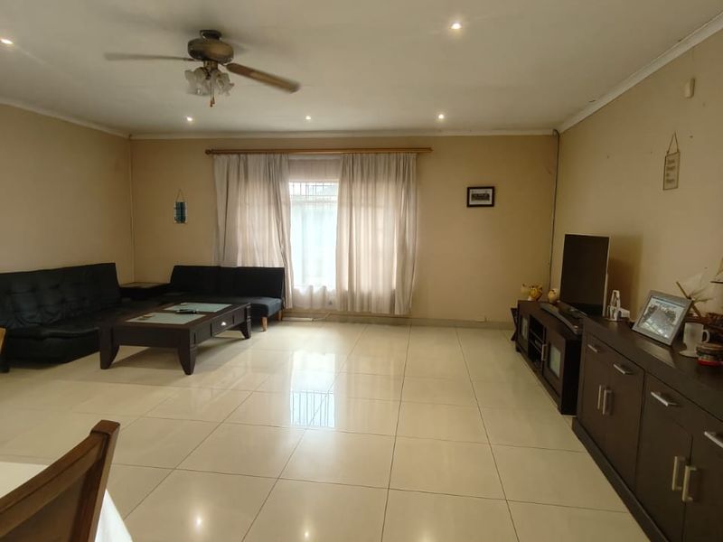 Spacious living room featuring large format floor tiles, recessed downlighting, and a ceiling fan, offering a neutral canvas for interior updates.