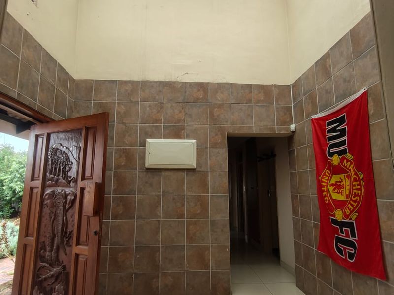 Entrance hall featuring a high ceiling with a large skylight, tiled walls, and a decorative carved wooden front door.