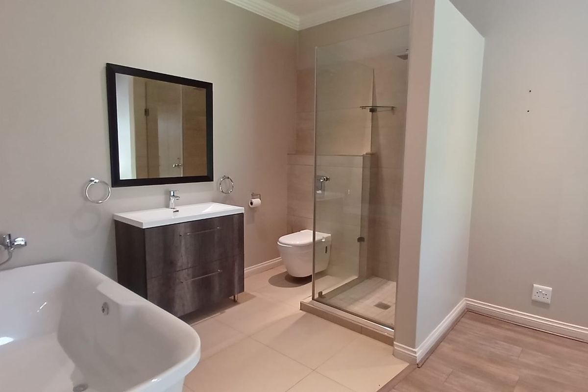 Modern bathroom featuring a freestanding bathtub, a floating vanity with a basin, and a glass-enclosed walk-in shower with neutral tiling.