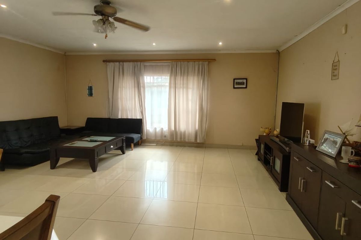 Spacious living area featuring large format floor tiles, recessed downlighting, and a ceiling fan, offering a neutral canvas for interior design.