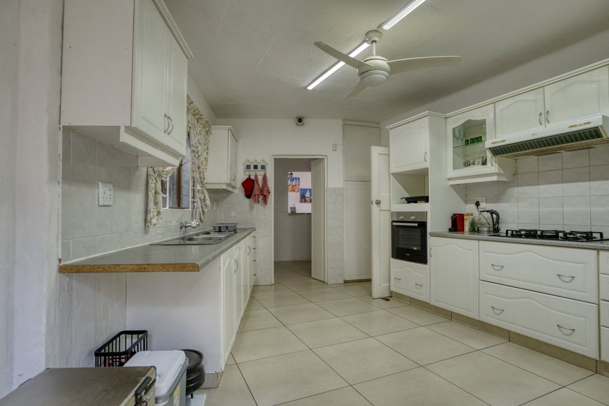 Functional kitchen featuring white cabinetry, laminate countertops, built-in oven, gas hob, and tiled flooring, offering a practical layout for daily meal preparation.
