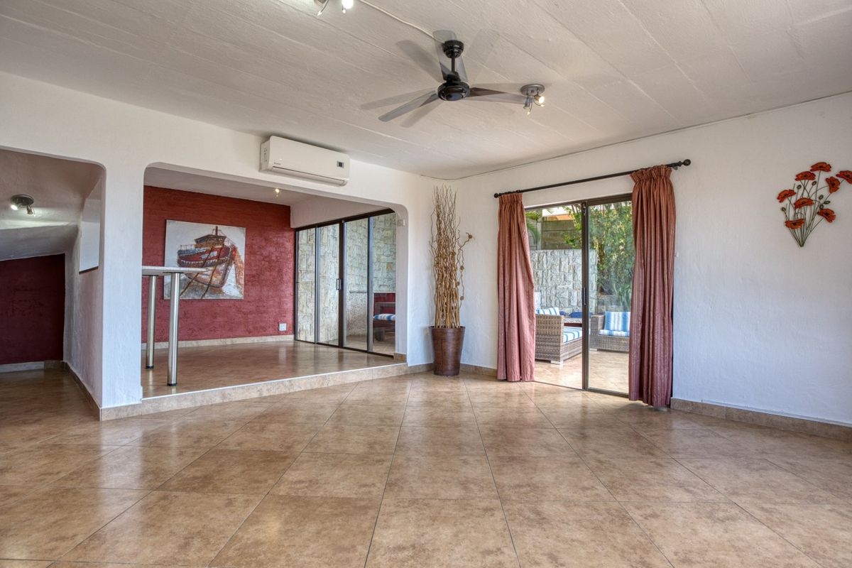 Spacious living area featuring tiled flooring, a ceiling fan, split-system air conditioning, and sliding glass doors leading to an outdoor patio.