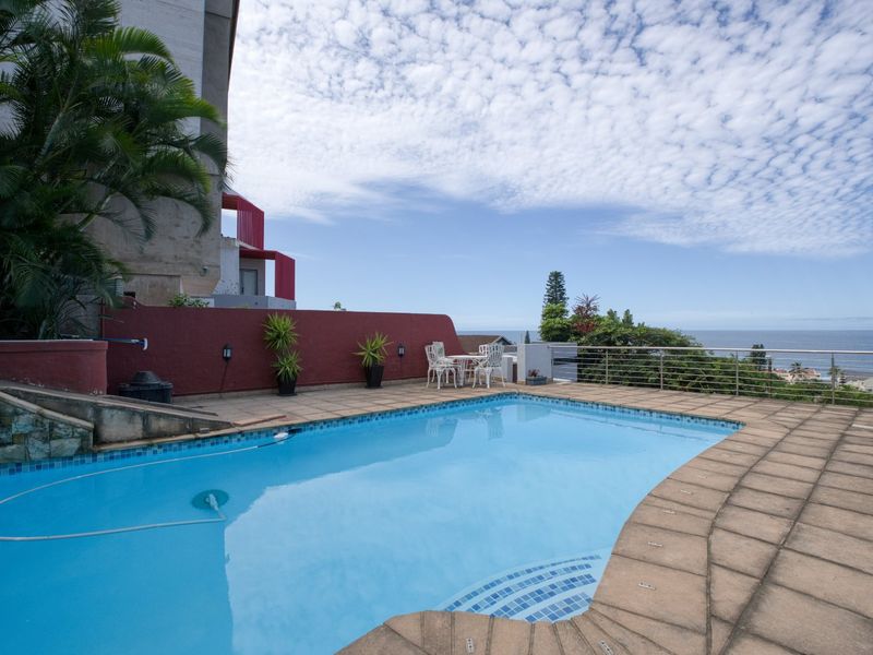 Outdoor pool area featuring a tiled deck, stainless steel balustrade, and ocean views, providing a functional space for relaxation and entertainment.