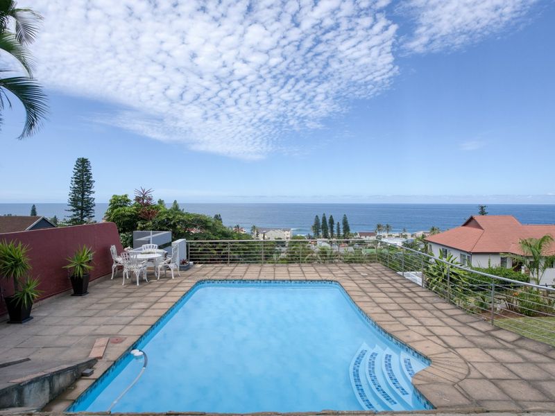 Outdoor pool area featuring a tiled deck, stainless steel balustrades, and expansive ocean views.