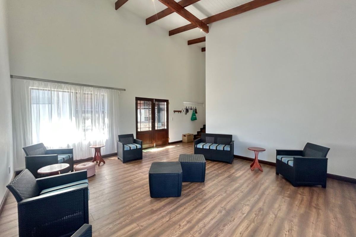 Spacious living area featuring high vaulted ceilings with exposed timber beams and durable wood-look flooring, creating an open and airy atmosphere.