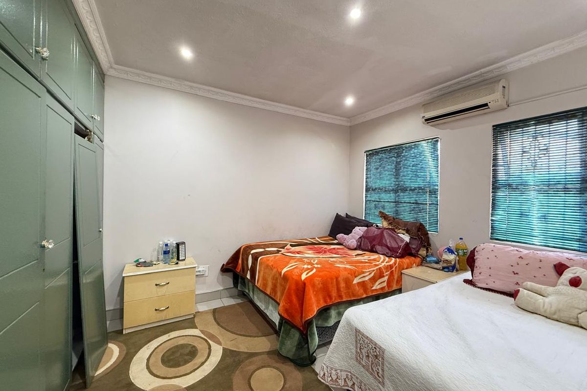 A bedroom featuring built-in sage green cabinetry, recessed ceiling lighting, and a wall-mounted air conditioning unit.