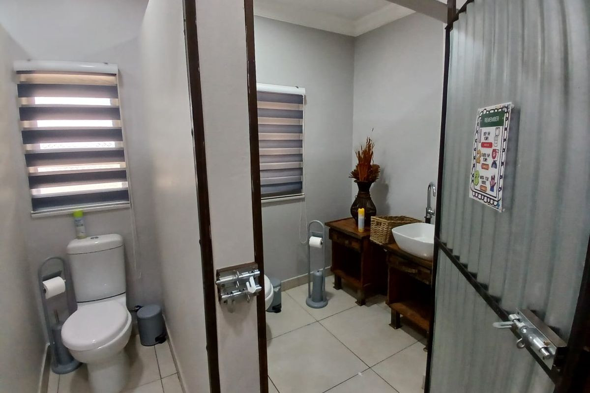 A functional bathroom featuring a separate toilet cubicle, tiled flooring, and a vanity area with a vessel sink.