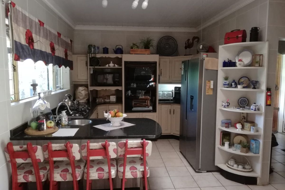 A functional kitchen featuring dark granite countertops, built-in oven, gas hob, and tiled flooring with ample storage cabinetry.