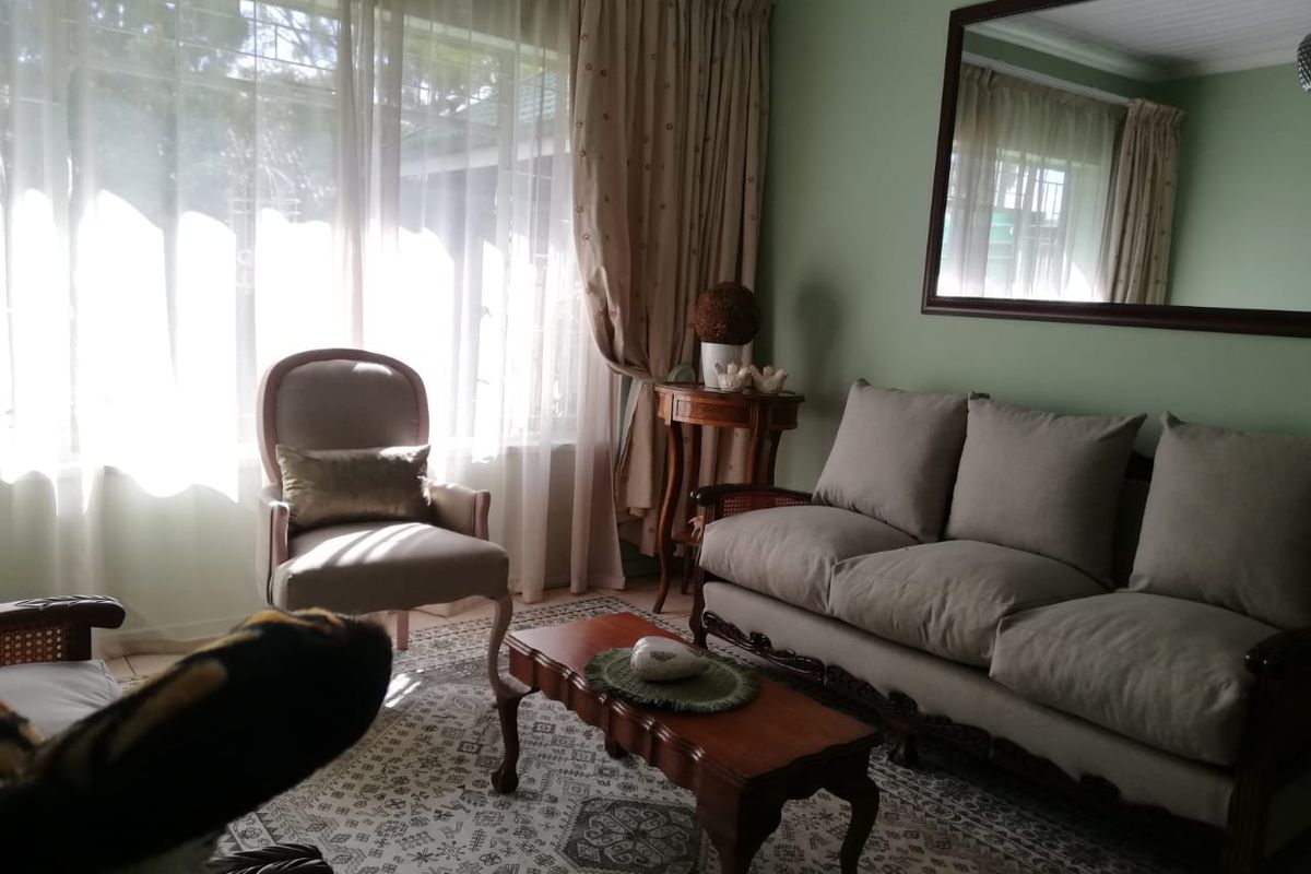 A cozy living room featuring large windows with natural light, neutral wall tones, and a classic layout suitable for comfortable family living.