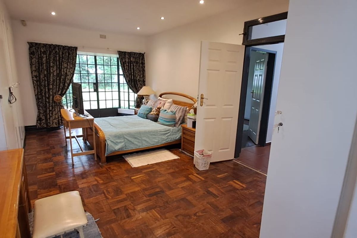 Spacious bedroom featuring classic parquet flooring, recessed ceiling lighting, and large windows with direct access to the exterior.