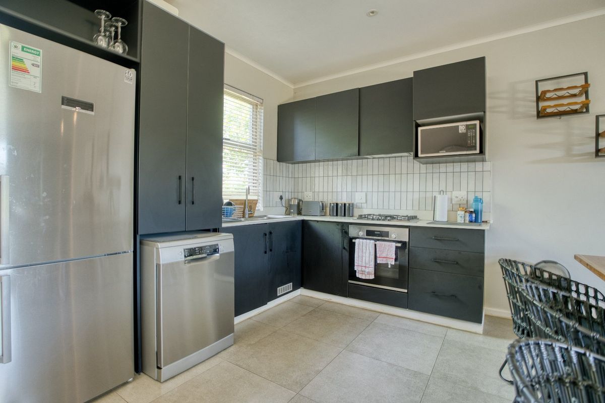 Modern kitchen featuring dark cabinetry, subway tile backsplash, built-in oven, gas hob, and integrated stainless steel appliances.