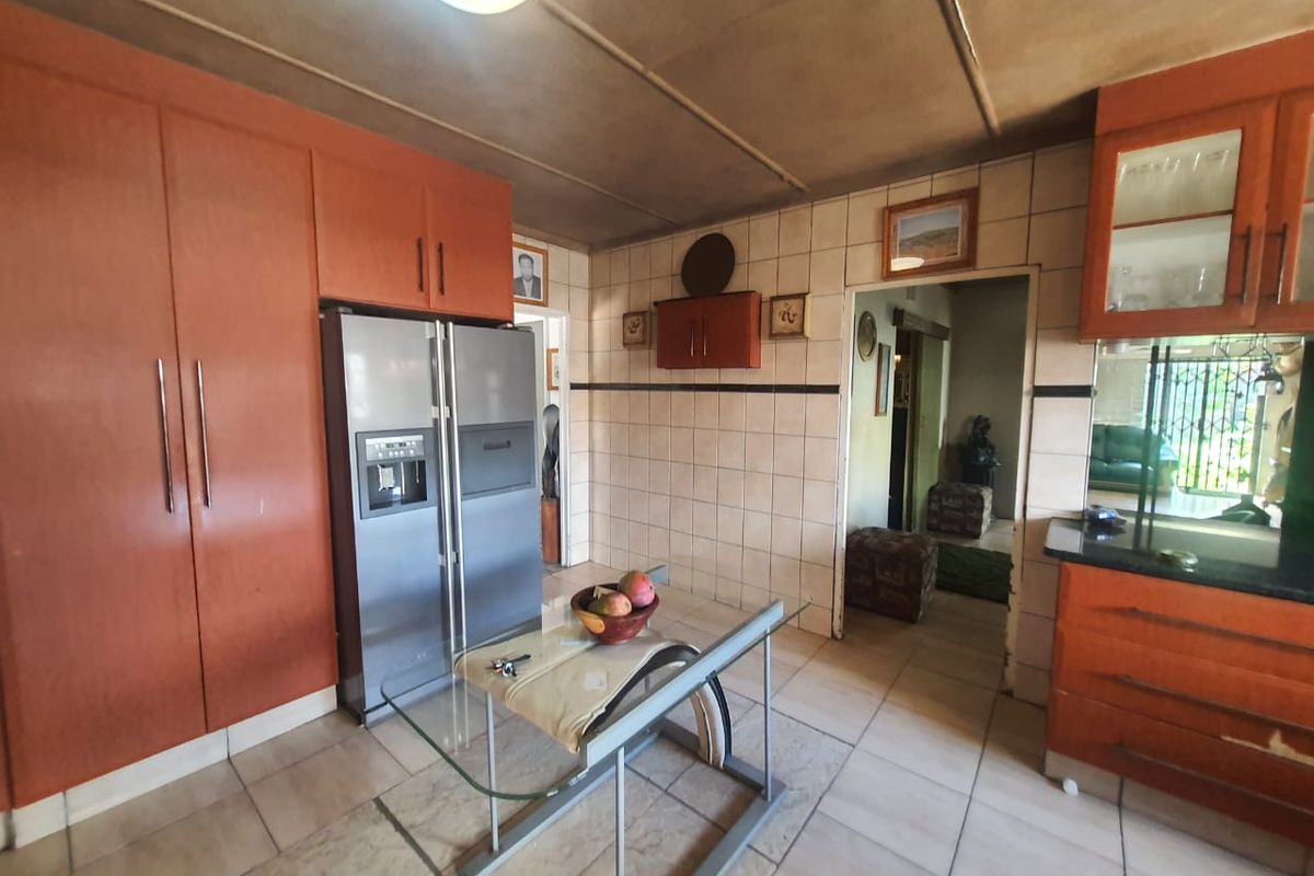 A dated kitchen featuring built-in wooden cabinetry, tiled walls, and tiled flooring, offering potential for modernization and renovation.