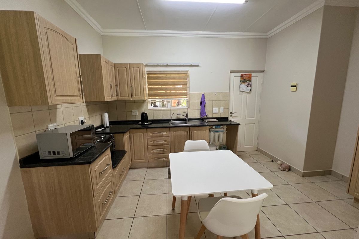 Functional kitchen featuring light wood cabinetry, granite countertops, tiled flooring, and a tiled backsplash, offering a practical layout for daily use.
