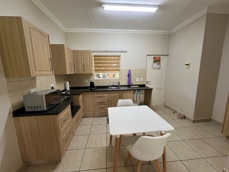 Functional kitchen featuring light wood cabinetry, granite countertops, tiled flooring, and a tiled backsplash, offering a practical layout for daily use.