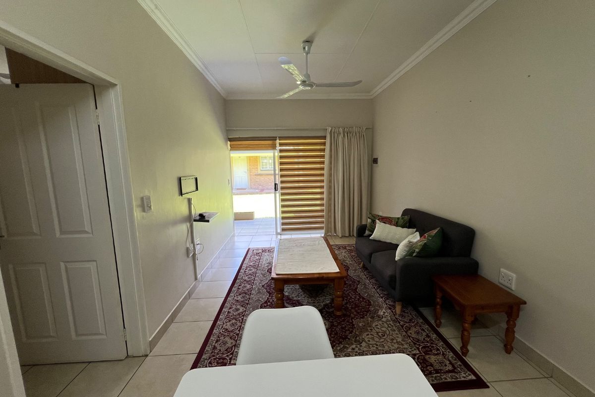 A functional living room featuring tiled flooring, a ceiling fan, and a sliding glass door providing access to an outdoor patio area.