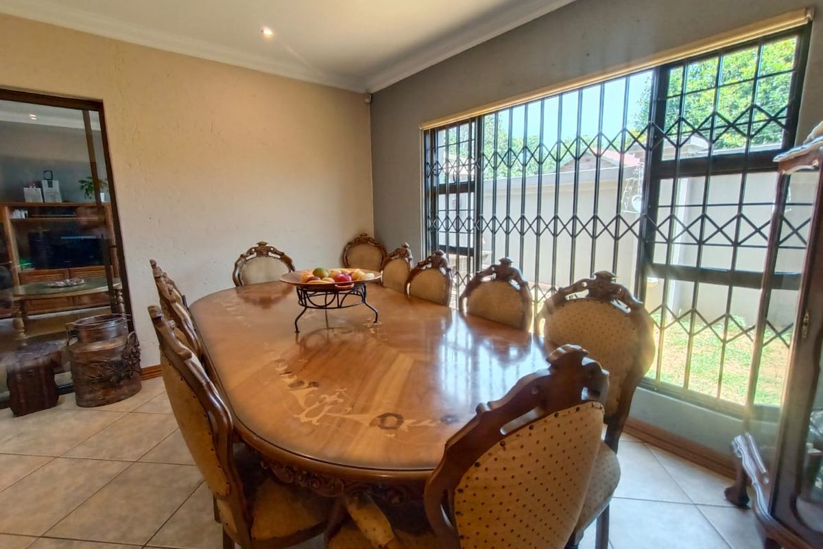 A dining room featuring tiled flooring and a large window fitted with security bars, providing natural light and access to the exterior.