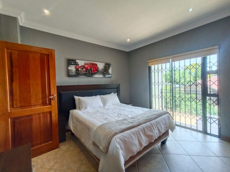 A bedroom featuring tiled flooring, recessed ceiling lighting, and a sliding door with security gate leading to a balcony.