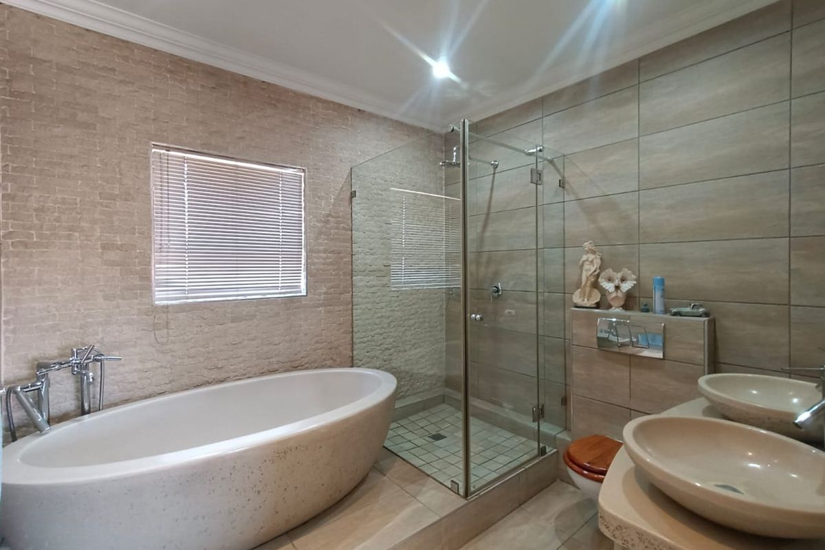 Modern bathroom featuring a freestanding bathtub, a glass-enclosed walk-in shower, and dual vessel sinks set on a stone vanity.