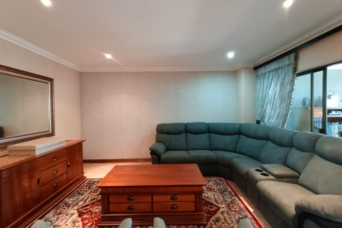A comfortable living room featuring recessed ceiling lighting, crown molding, and large sliding glass doors leading to an outdoor area.