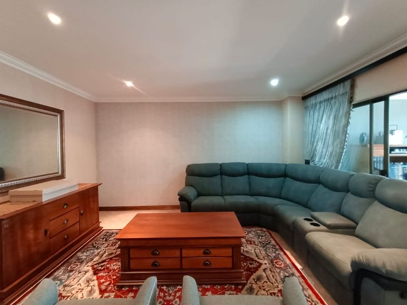 A comfortable living room featuring recessed ceiling lighting, crown molding, and large sliding glass doors leading to an outdoor area.