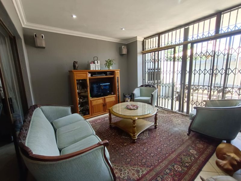 A living room featuring tiled flooring, recessed ceiling lighting, and large sliding glass doors with security gates leading to an outdoor area.