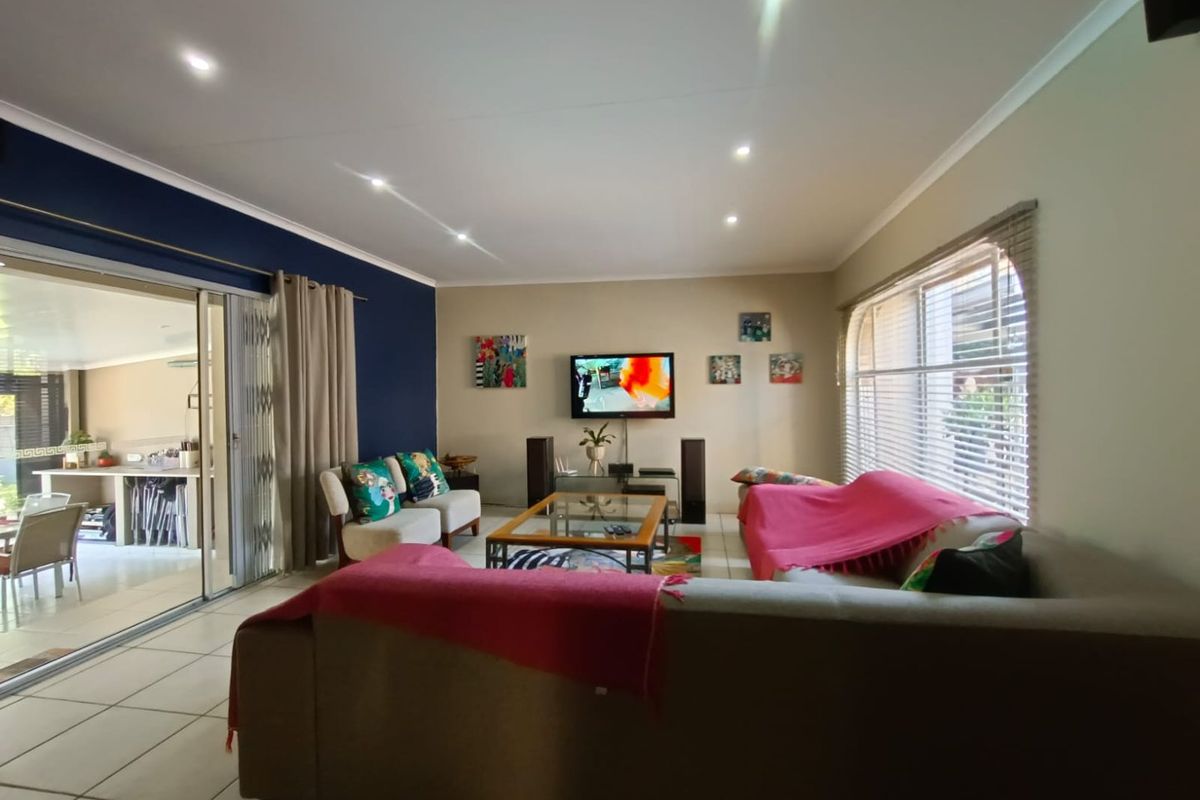 Spacious living room featuring tiled flooring, recessed downlighting, and large sliding glass doors providing seamless access to the outdoor patio area.