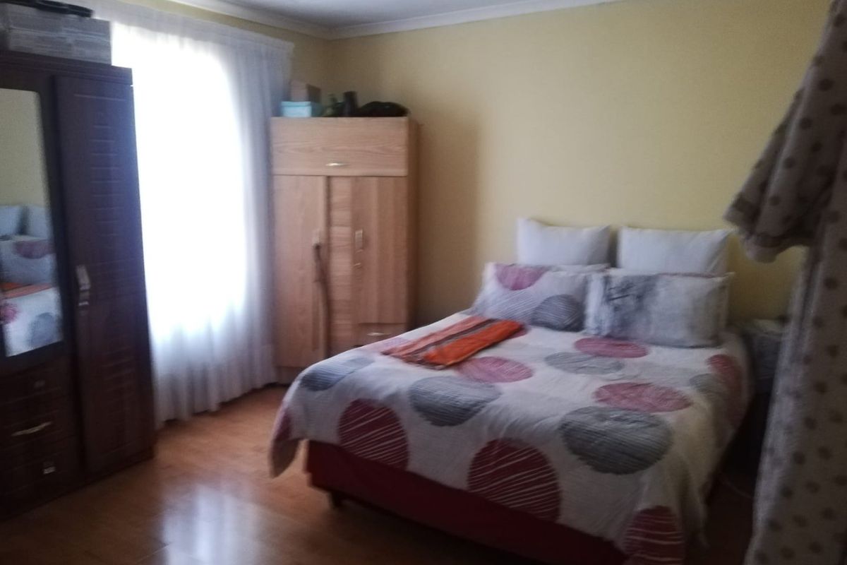 A bedroom featuring laminate flooring and a window with curtains, providing a functional living space.