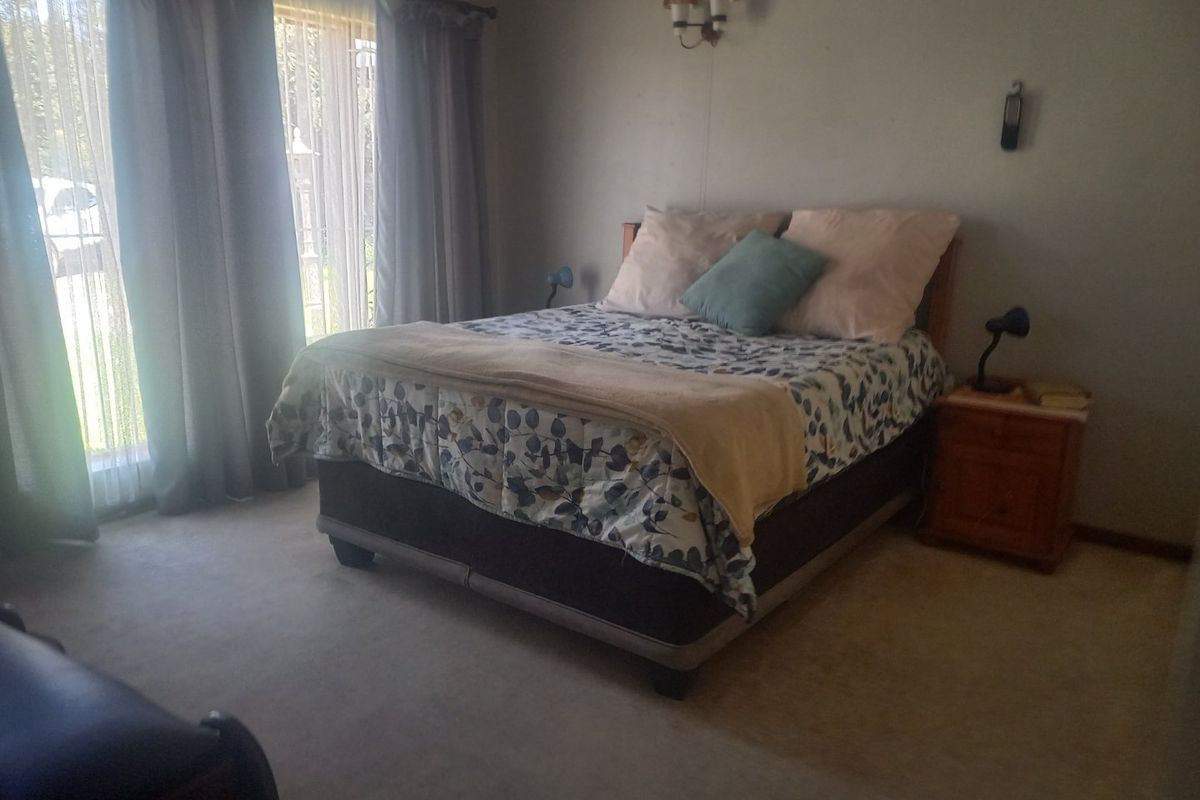A carpeted bedroom featuring a sliding glass door with curtains, providing natural light and access to the exterior.