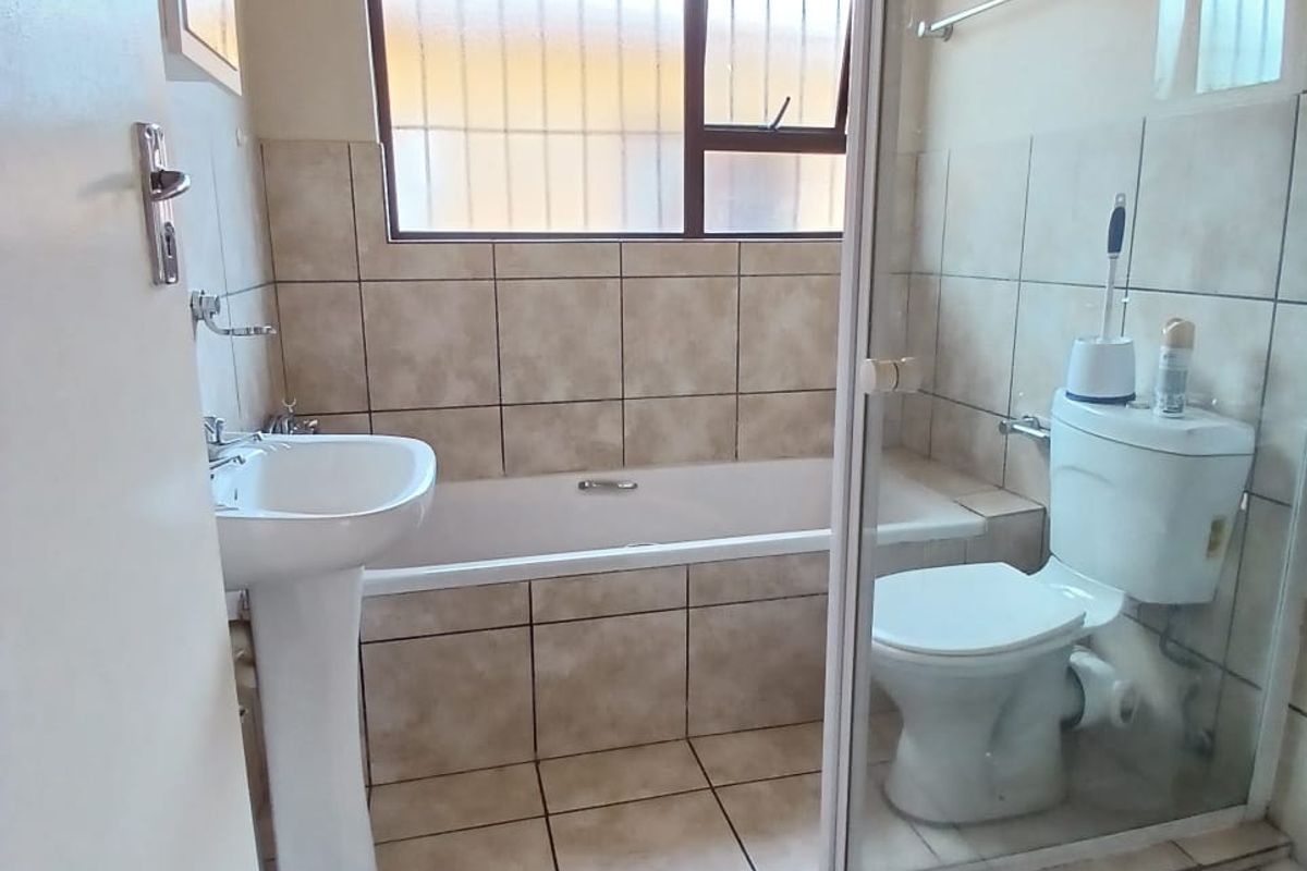 A functional bathroom featuring a pedestal basin, a built-in bathtub with tiled surround, and a separate glass-enclosed shower cubicle.