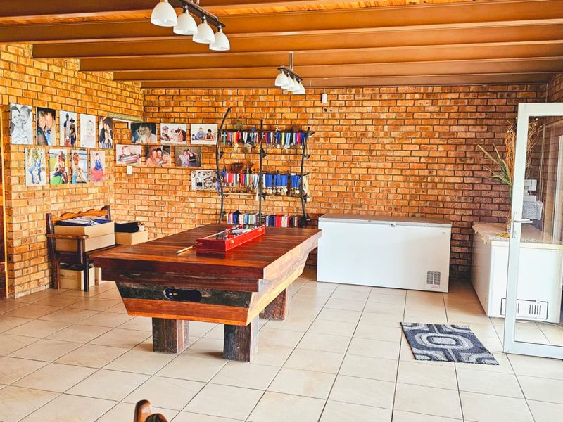 Spacious living area featuring exposed brick walls, timber beam ceilings, and ceramic floor tiles, offering a rustic aesthetic with potential for versatile use.