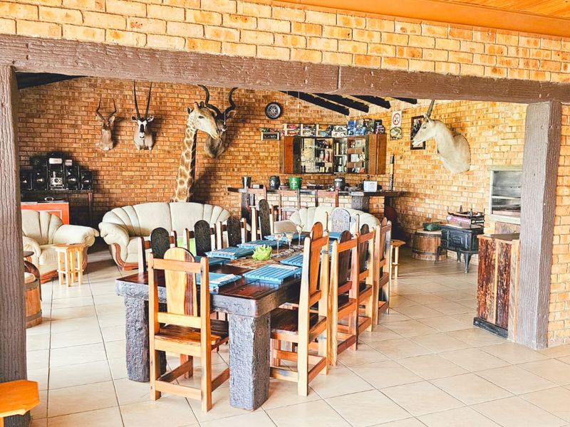 Spacious covered patio area featuring exposed brick walls, a built-in bar, and a built-in braai, ideal for outdoor entertaining.