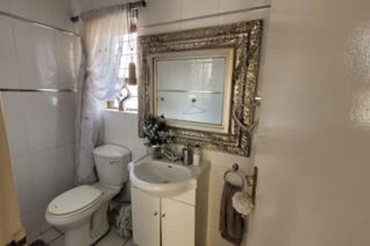 A compact bathroom featuring a white vanity with integrated basin, a standard toilet, and tiled wall finishes.