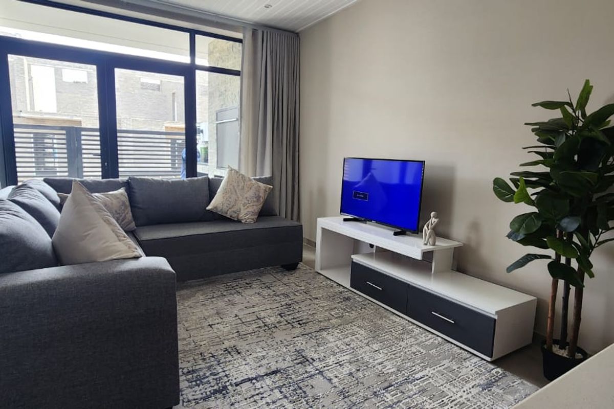 A modern living room featuring large glass sliding doors that provide access to an outdoor area, complemented by neutral wall finishes and tiled flooring.