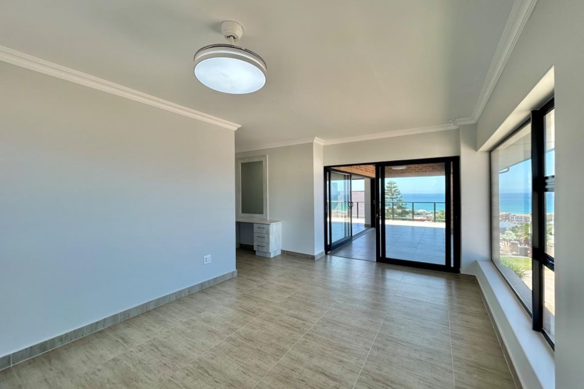 Bright and spacious living area featuring large sliding glass doors that open onto a balcony with scenic ocean views.