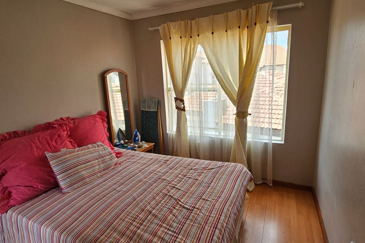 A standard bedroom featuring laminate flooring and a window with natural light, requiring minor cosmetic updates to the wall finishes.
