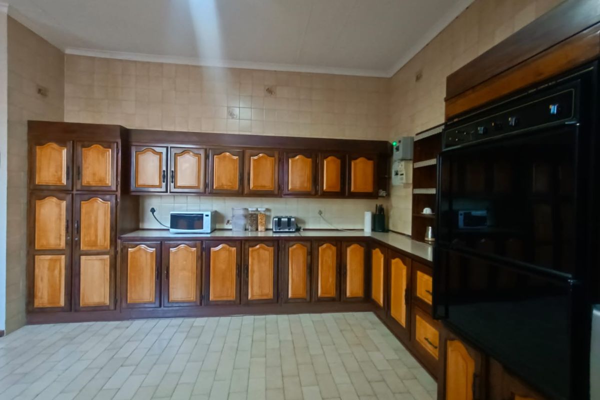 A spacious kitchen featuring extensive wooden cabinetry, tiled walls, and a built-in double oven, offering a functional layout with ample storage space.