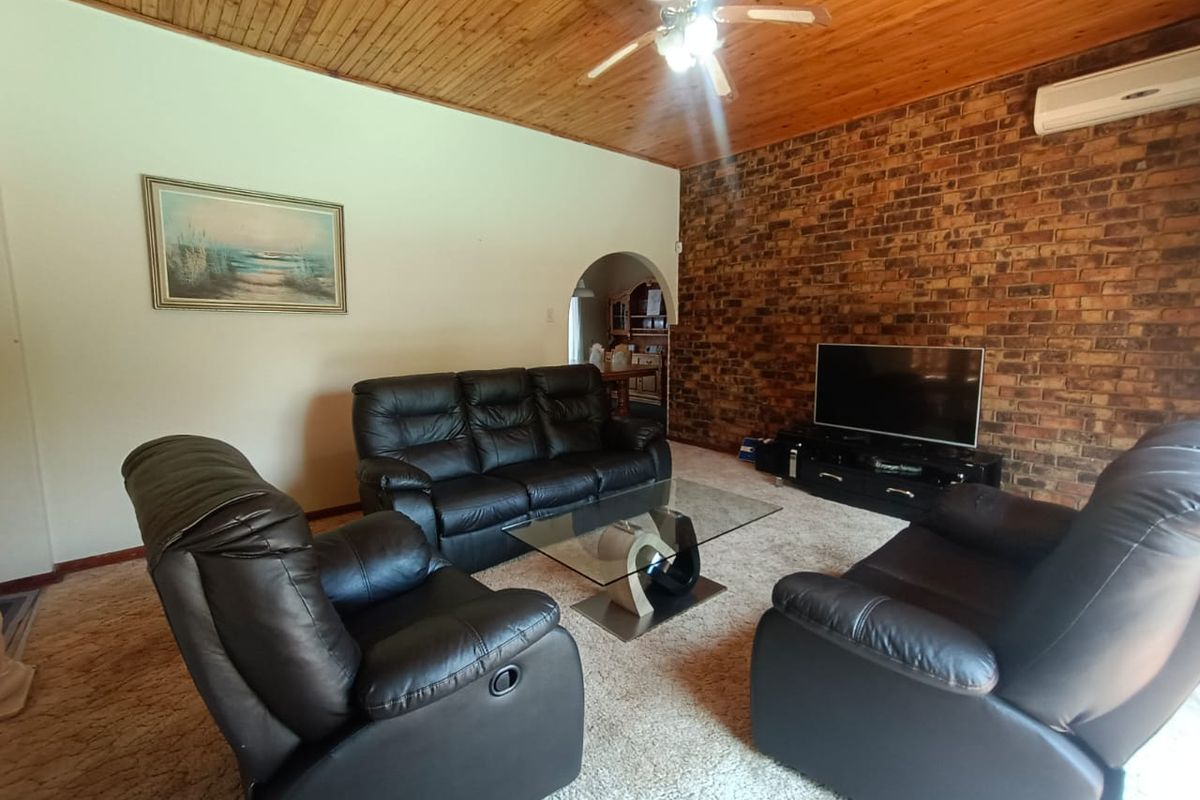 Living room featuring a prominent exposed brick feature wall, timber-clad ceiling with integrated fan, and split-system air conditioning unit.