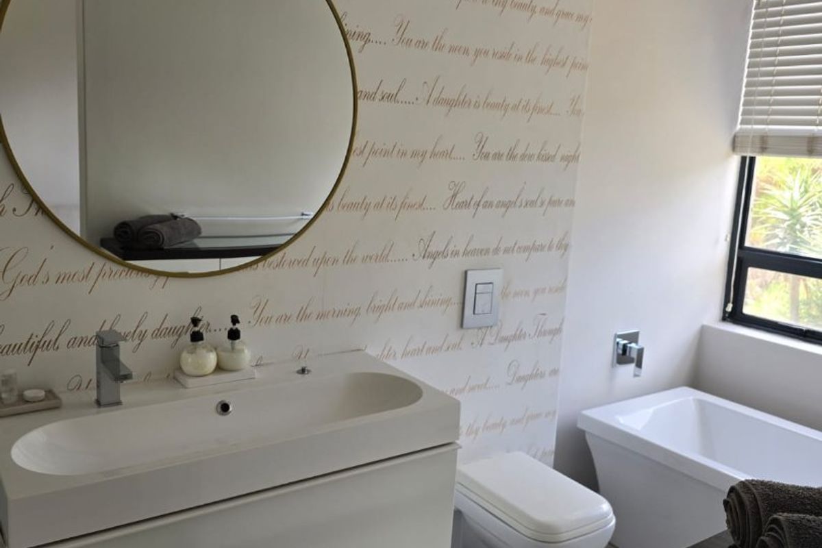 Modern bathroom featuring a wall-mounted vanity with integrated basin, wall-hung toilet, and a deep soaking tub with tiled flooring.