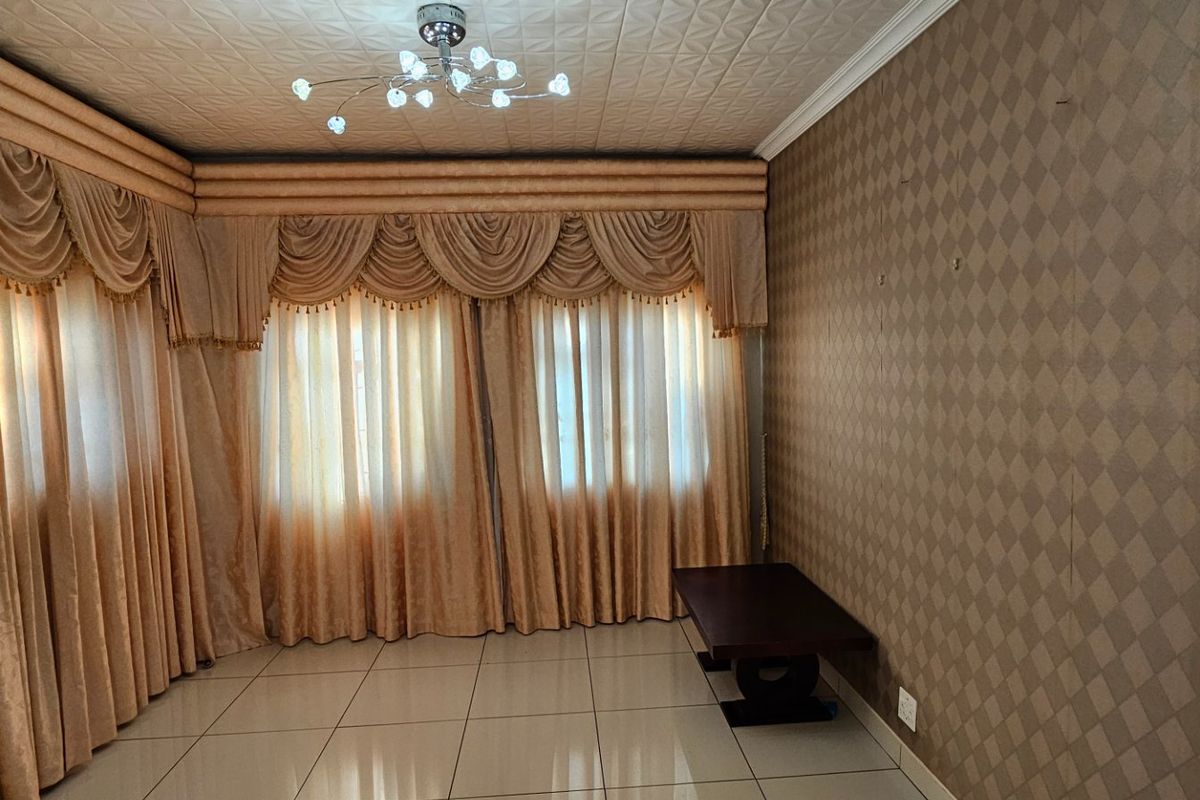 A living room featuring tiled flooring, patterned wallpaper, and decorative curtain pelmets with integrated lighting fixtures.