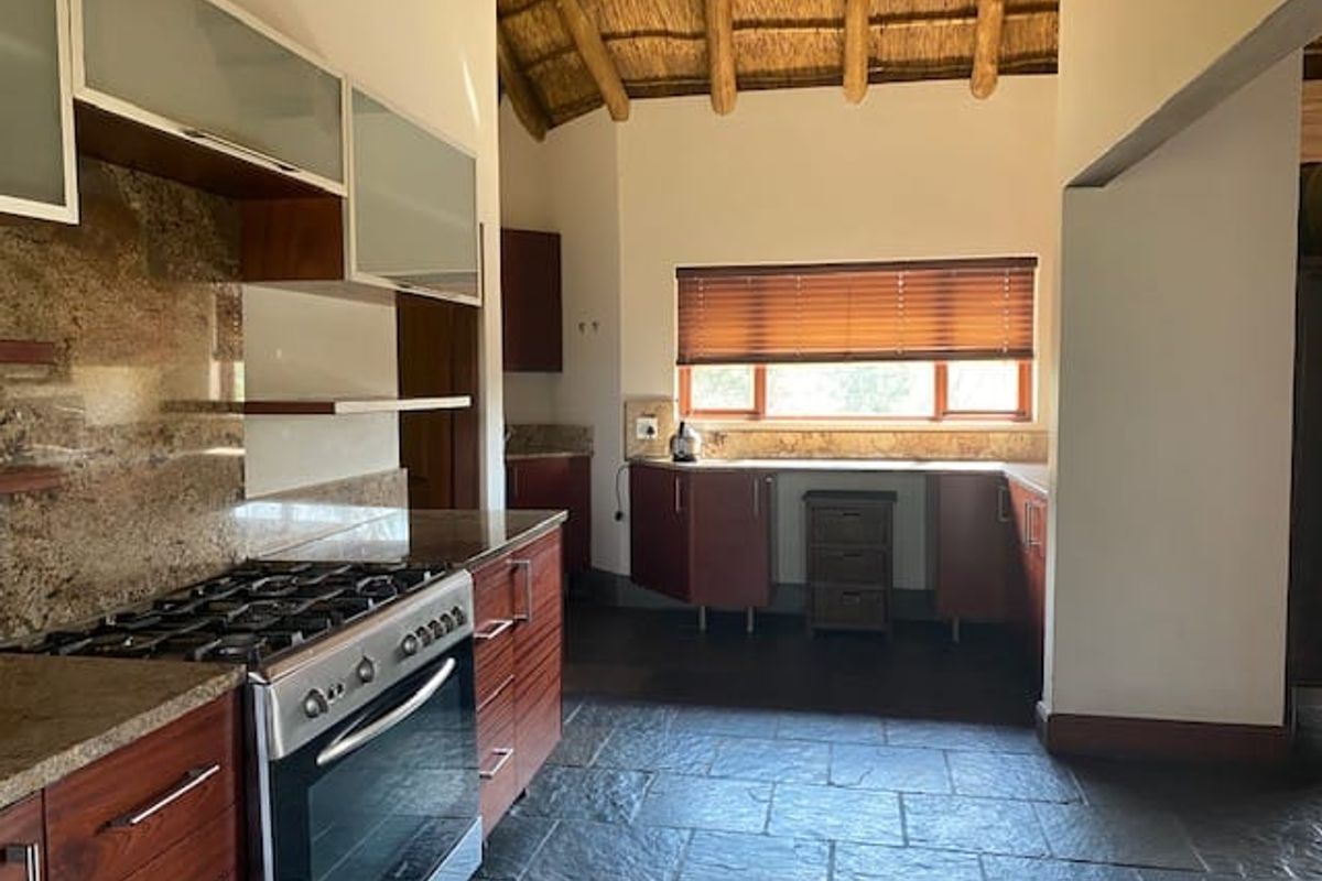 Spacious kitchen featuring granite countertops, gas stove, built-in oven, slate flooring, and a unique high-vaulted thatched ceiling.
