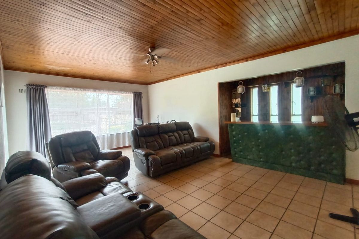 Spacious living room featuring a timber tongue and groove ceiling, tiled flooring, and a built-in bar area.