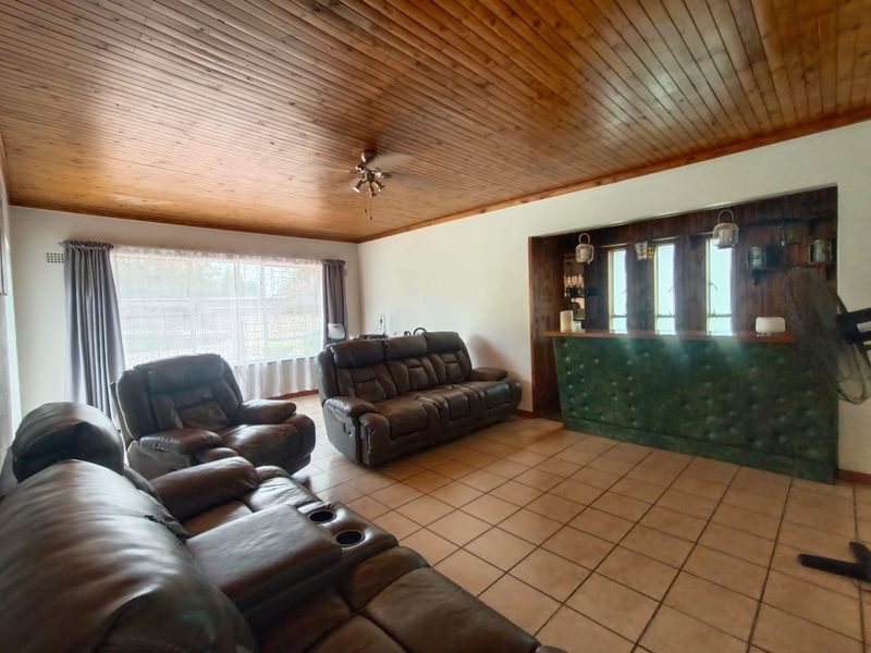 Spacious living room featuring a timber tongue and groove ceiling, tiled flooring, and a built-in bar area.