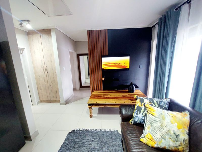 A modern living room featuring tiled flooring, built-in cabinetry, and a decorative slatted wood feature wall with a mounted television.