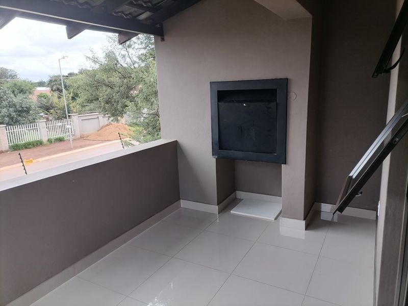 A covered balcony featuring tiled flooring and a built-in braai, offering an ideal space for outdoor entertaining.